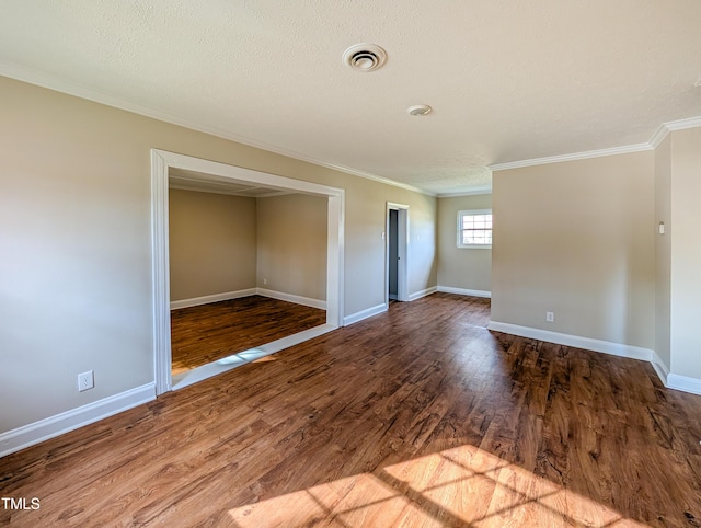 unfurnished room featuring a textured ceiling, wood finished floors, visible vents, baseboards, and crown molding