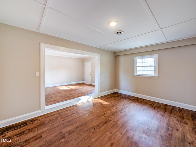 spare room with visible vents, baseboards, and wood finished floors