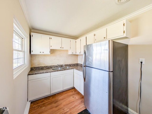 kitchen with dark countertops, crown molding, a sink, and freestanding refrigerator