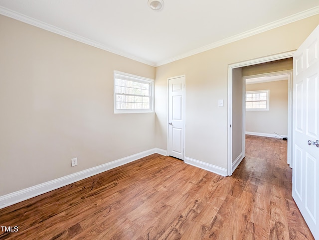 spare room featuring light wood-style flooring, baseboards, and crown molding