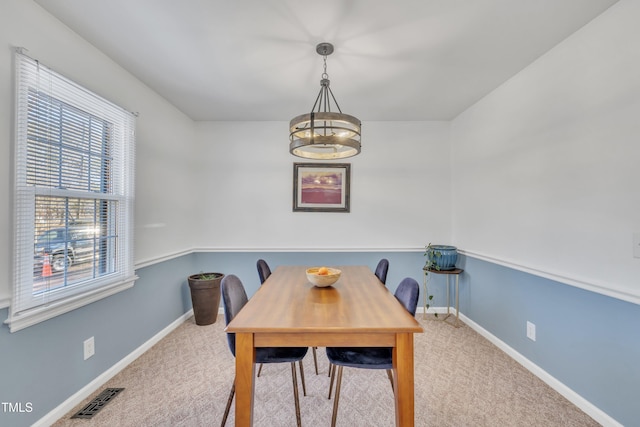 carpeted dining room with baseboards and visible vents