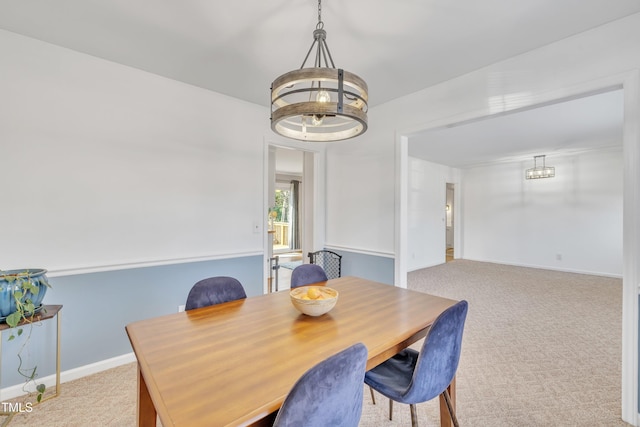 dining space featuring an inviting chandelier, baseboards, and light colored carpet