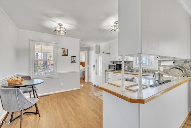 kitchen featuring a healthy amount of sunlight, stainless steel microwave, light countertops, and ornamental molding