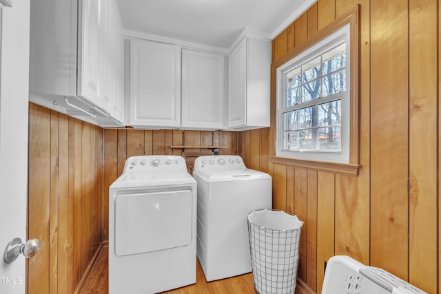 laundry area featuring cabinet space, wood walls, and washer and clothes dryer