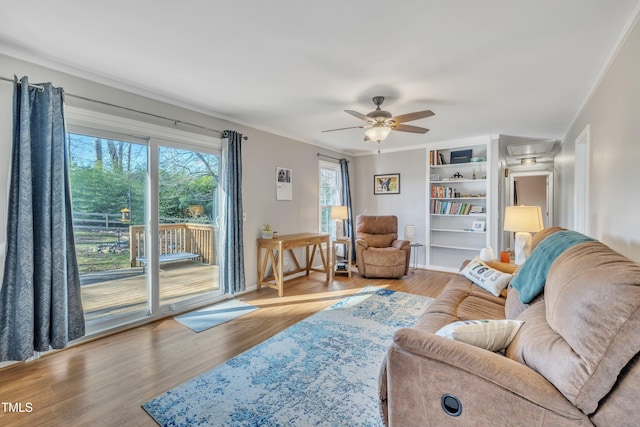 living area featuring ornamental molding, baseboards, ceiling fan, and light wood finished floors