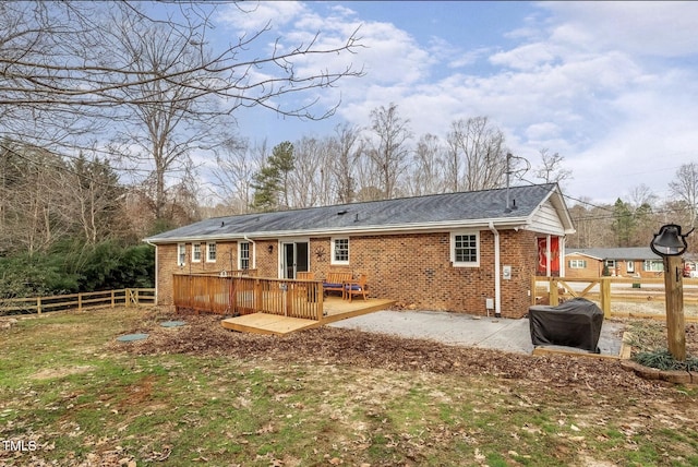 rear view of property featuring brick siding, a patio area, fence, and a wooden deck