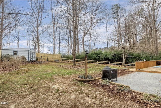 view of yard with a storage shed, fence, a deck, and an outbuilding