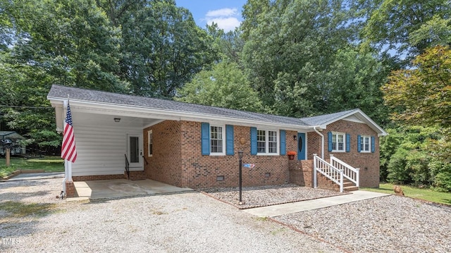 ranch-style house with gravel driveway, an attached carport, brick siding, and crawl space