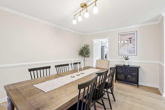 dining area featuring crown molding, baseboards, and light wood-style floors