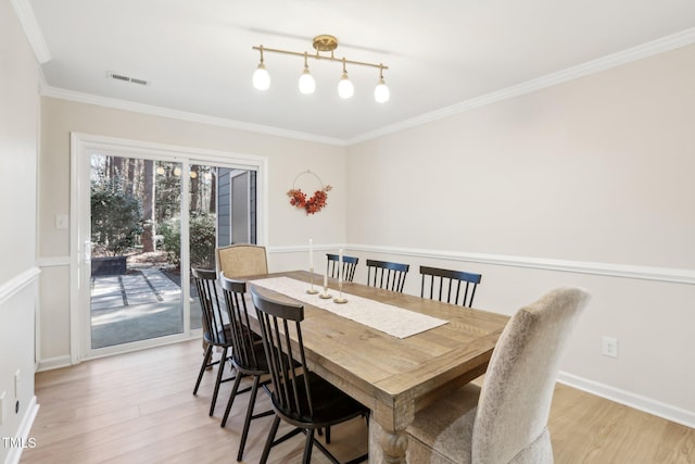 dining space with baseboards, light wood-type flooring, visible vents, and crown molding