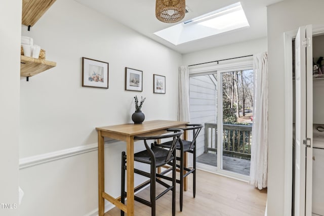 dining area with a skylight and light wood-style floors