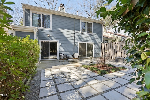 back of property featuring a patio area, a chimney, and fence