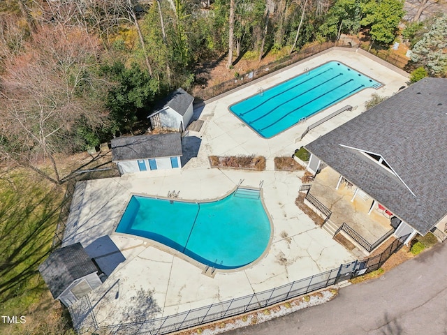 pool with fence, an outdoor structure, and a patio