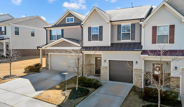 townhome / multi-family property featuring an attached garage, a standing seam roof, concrete driveway, and brick siding