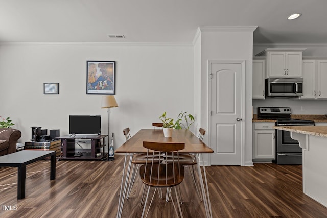 kitchen with dark wood-style floors, appliances with stainless steel finishes, visible vents, and crown molding