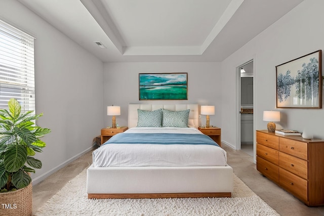 bedroom with light colored carpet, a raised ceiling, visible vents, and baseboards