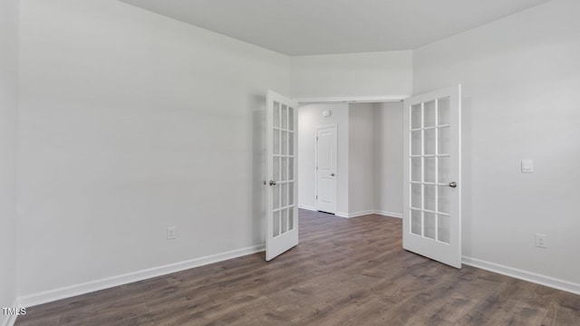 spare room featuring baseboards, dark wood finished floors, and french doors