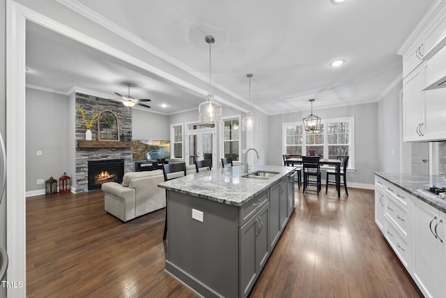 kitchen with gray cabinetry, a sink, dark wood-style floors, a fireplace, and crown molding