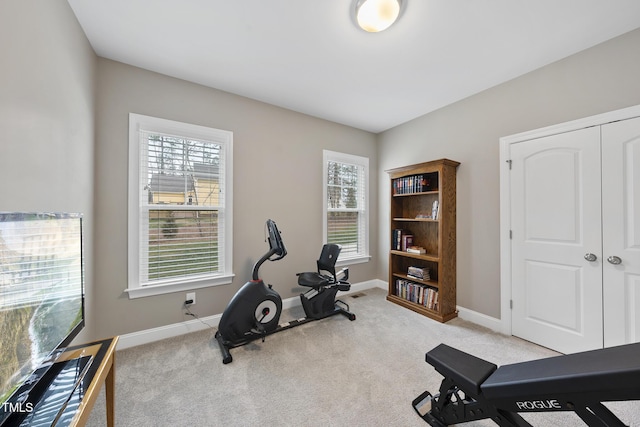 exercise room featuring light colored carpet and baseboards