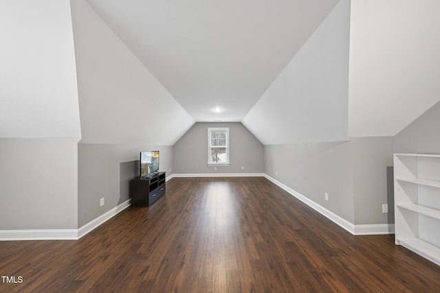 additional living space with baseboards, lofted ceiling, and dark wood finished floors