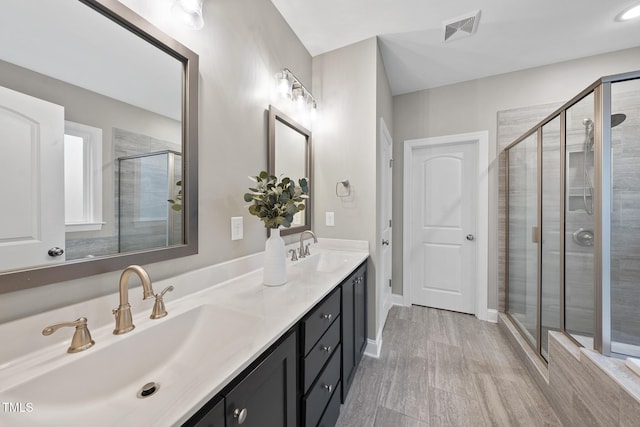 bathroom with double vanity, a stall shower, visible vents, and a sink