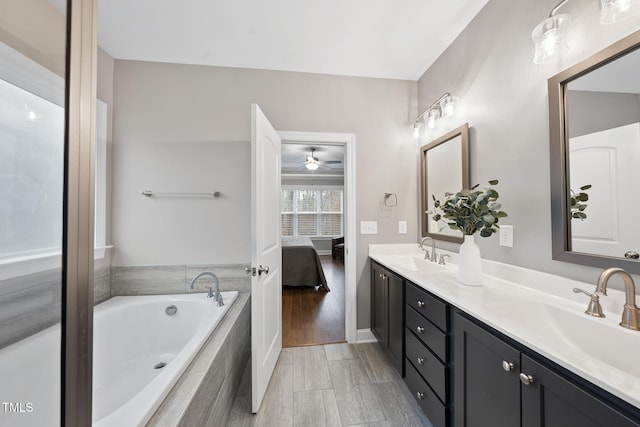 bathroom with double vanity, connected bathroom, tiled bath, and a sink