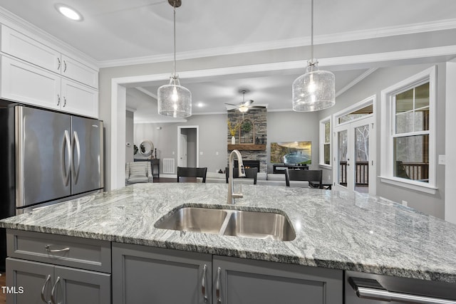 kitchen with a stone fireplace, ornamental molding, gray cabinetry, and a sink