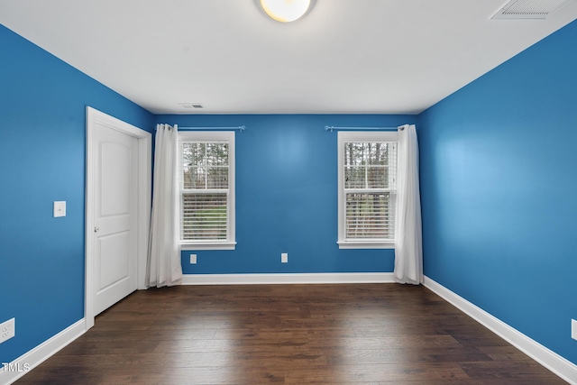 unfurnished room with wood finished floors, visible vents, and a healthy amount of sunlight