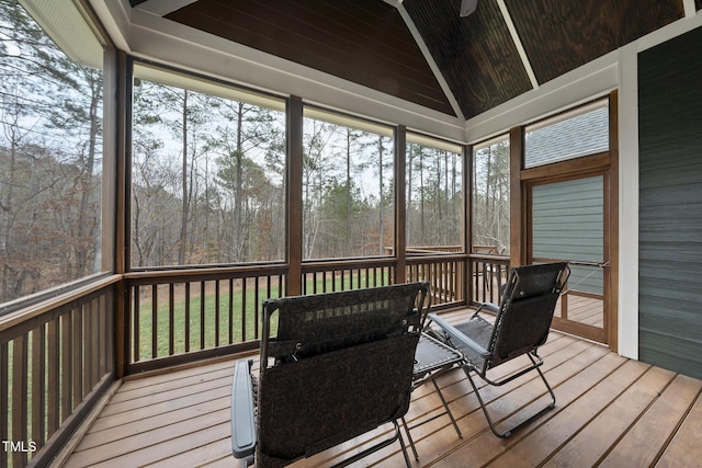 sunroom featuring lofted ceiling and a wooded view