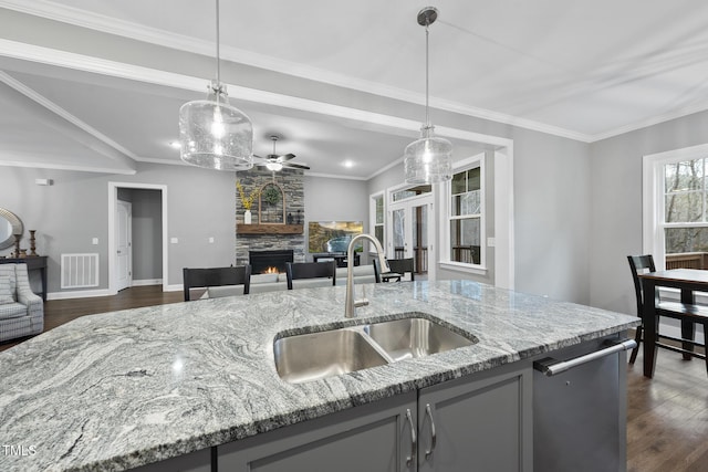 kitchen with a stone fireplace, visible vents, open floor plan, and a sink