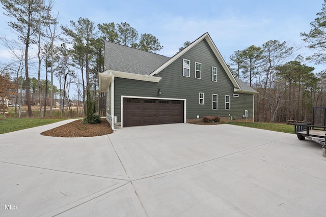 view of home's exterior with driveway and a shingled roof