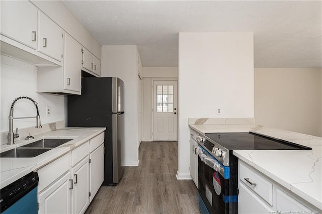 kitchen featuring white cabinets, light wood-style flooring, appliances with stainless steel finishes, a textured ceiling, and a sink