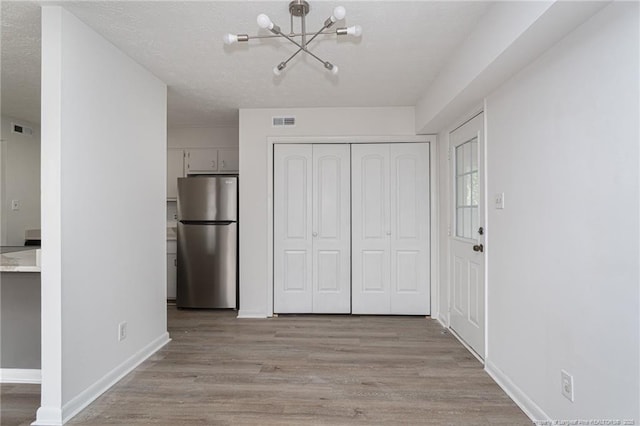 interior space with baseboards, visible vents, light wood finished floors, and an inviting chandelier