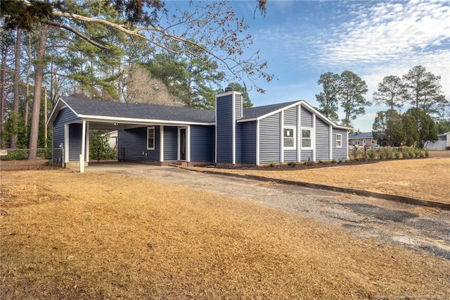 view of front of property with driveway, a chimney, and an attached carport