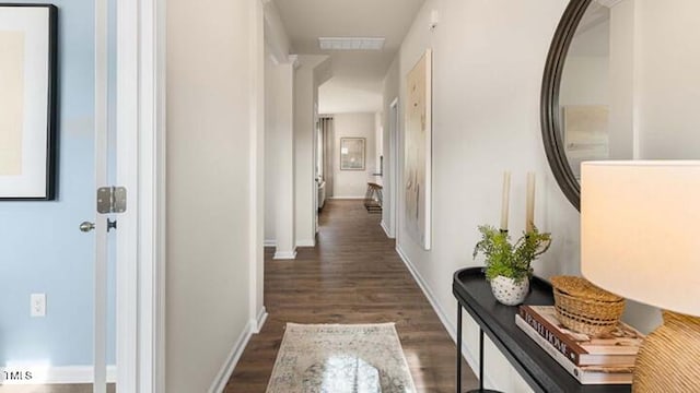 hallway featuring dark wood-type flooring, visible vents, and baseboards