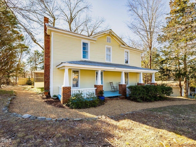 view of front of home featuring covered porch, metal roof, and a chimney