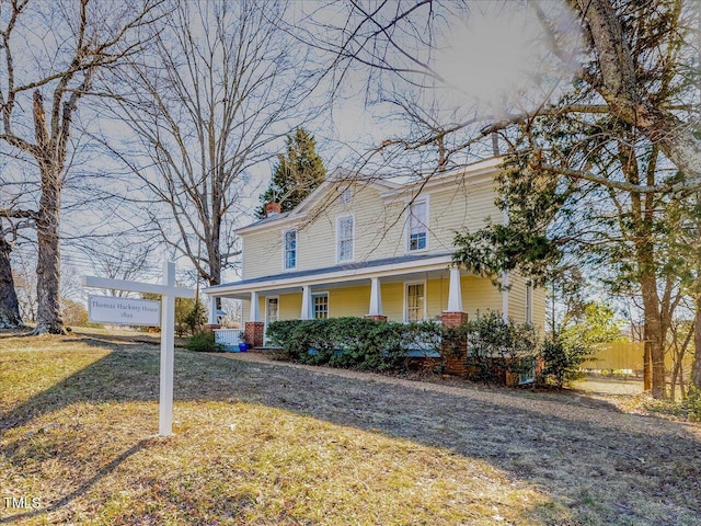 farmhouse inspired home featuring covered porch, a chimney, and a front yard