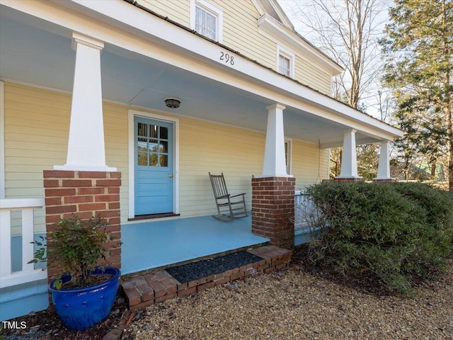 entrance to property with covered porch and brick siding