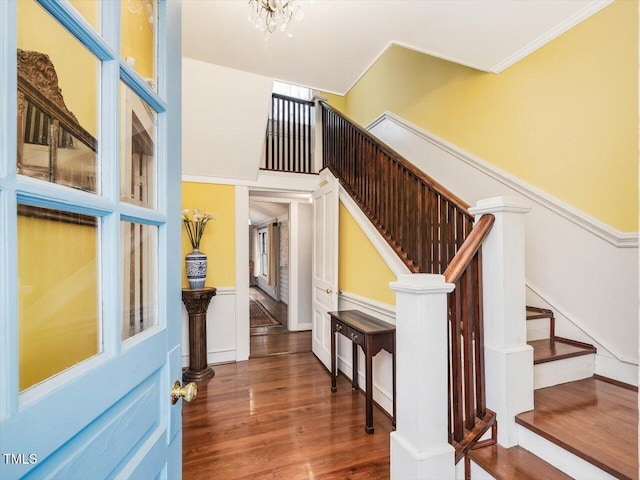 staircase featuring a wainscoted wall, an inviting chandelier, and wood finished floors