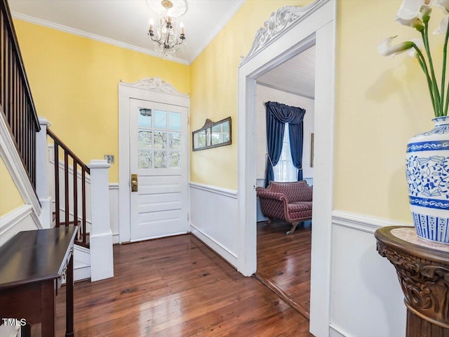 entryway with a wainscoted wall, dark wood-type flooring, stairs, crown molding, and a chandelier