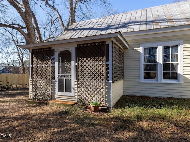 view of side of home with metal roof, a standing seam roof, and fence