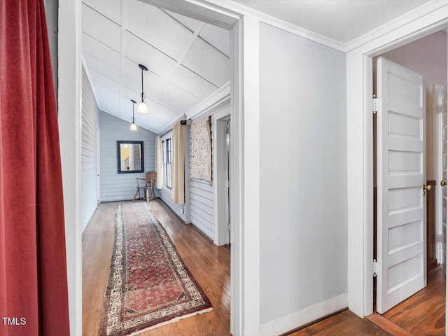 hallway with lofted ceiling, baseboards, ornamental molding, and wood finished floors