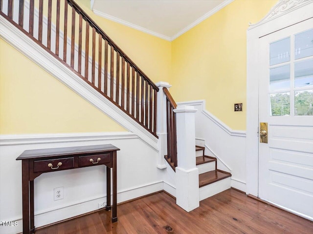 stairs with baseboards, wood finished floors, and crown molding