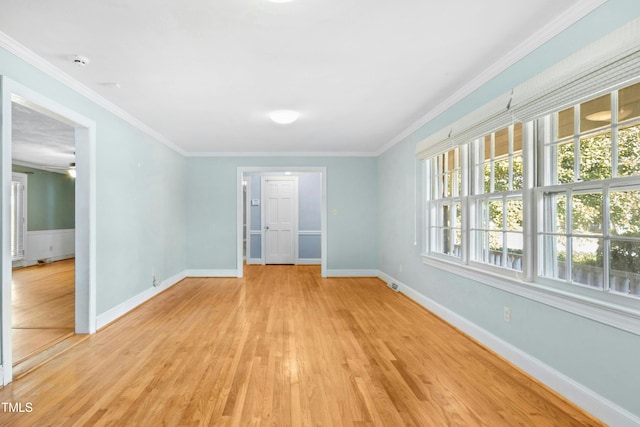 spare room featuring baseboards, light wood finished floors, and crown molding