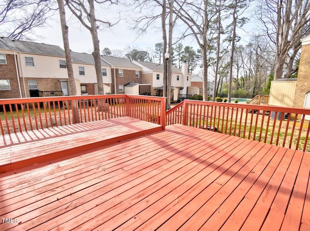 wooden terrace featuring an outdoor structure, a residential view, and a shed