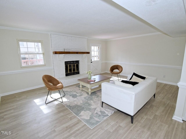 living area with wood finished floors, a fireplace, baseboards, and ornamental molding