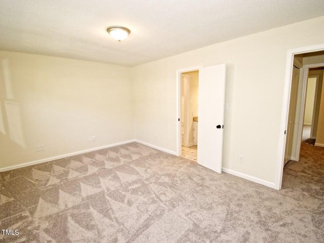 unfurnished room featuring a textured ceiling, baseboards, and carpet