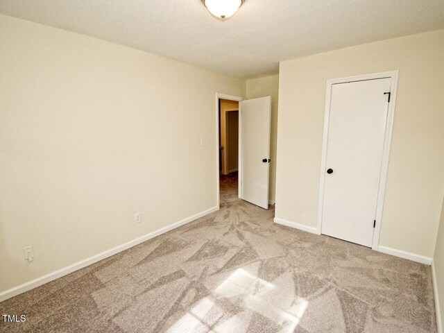 unfurnished bedroom featuring a textured ceiling, baseboards, and carpet