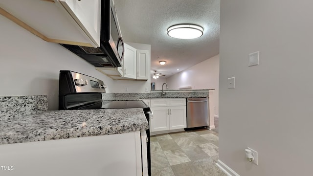 kitchen with light stone countertops, stainless steel appliances, a textured ceiling, white cabinetry, and a sink