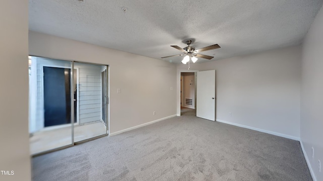 spare room featuring carpet floors, baseboards, visible vents, and a textured ceiling